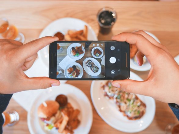 Person macht mit dem Handy ein Bild vom Essen für Social Media Marketing.
